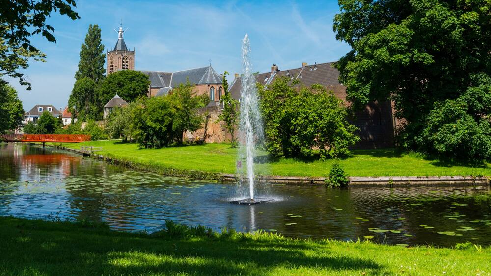 panorama view, canal with foutain and bridge, city wall, trees and church Grote Kerk in fortified city Vianen. The Netherlands