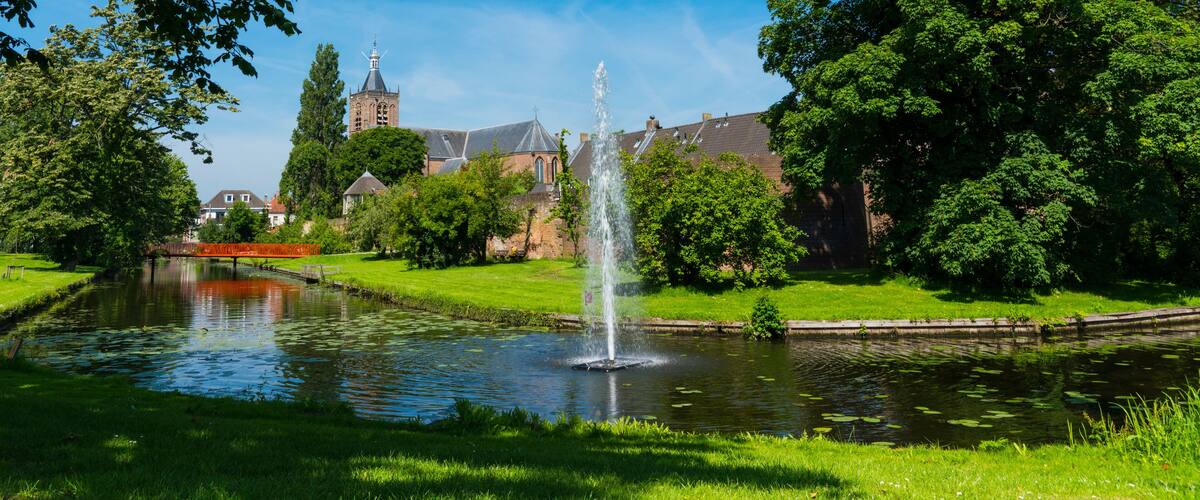 A fountain in a park with a church in the background.