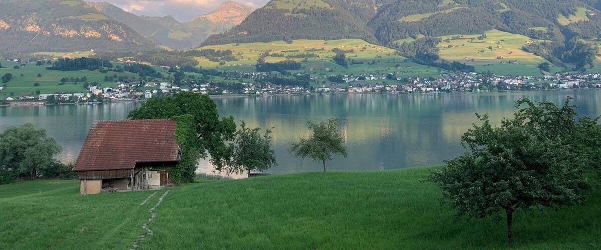 A lake surrounded by mountains, a small village, and a rustic building.