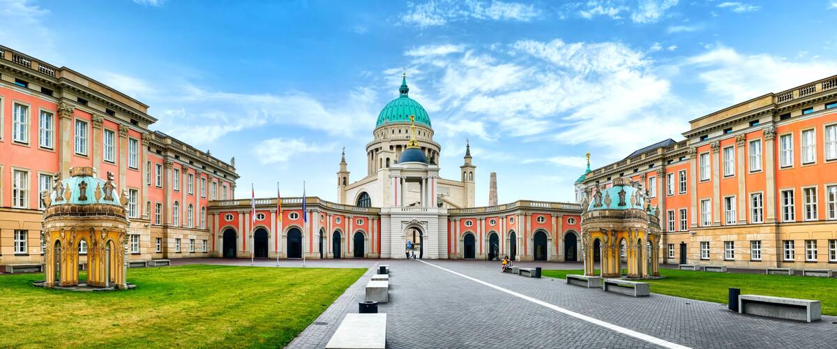 A grand building with a green dome, red and cream facades, and symmetrical architecture.
