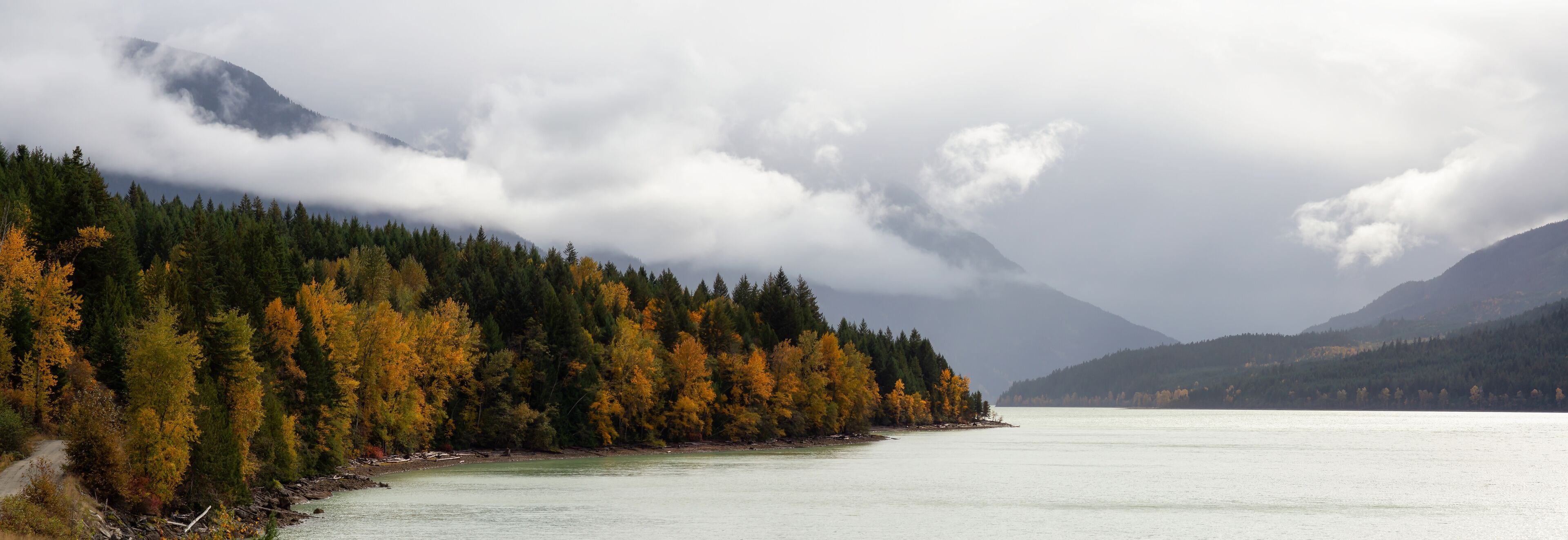A calm lake surrounded by autumn-colored trees and mountains.