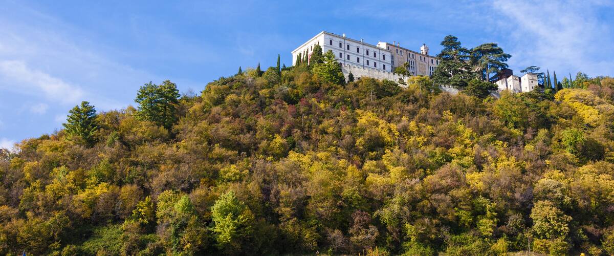 A large white building on a hill with autumn-colored trees.