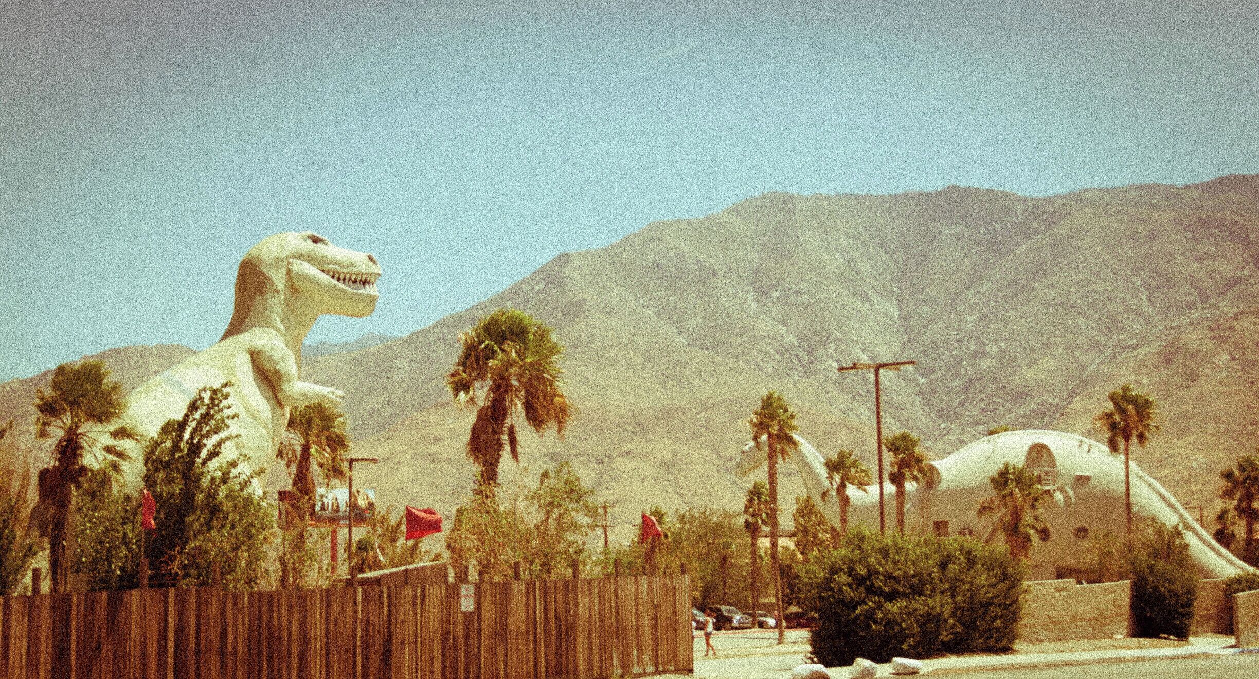 The creation of the Cabazon dinosaurs began in the 1960s by Knott's Berry Farm sculptor and portrait artist Claude K. Bell (1897–1988) to attract customers to his Wheel Inn Cafe, which opened in 1958 and is now closed. Dinny, the first of the Cabazon dinosaurs, was started in 1964 and created over a span of eleven years. Bell created Dinny out of spare material salvaged from the construction of nearby Interstate 10 at a cost of $300,000. The biomorphic building that was to become Dinny was first erected as steel framework over which an expanded metal grid was formed in the shape of a dinosaur. All of it was then covered with coats of shotcrete (spray concrete). Bell was quoted in 1970 as saying the 45-foot (14 m) high, 150-foot (46 m) long Dinny was "the first dinosaur in history, so far as I know, to be used as a building." His original vision for Dinny was for the dinosaur's eyes to glow and mouth to spit fire at night, predicting, "It'll scare the dickens out of a lot of people driving up over the pass." These two features, however, were not added. With the help of ironworker Gerald Hufstetler, Bell worked on the project independently; no construction companies or contractors were involved in the fabrication. The task of painting Dinny was completed by a friend of Bell's in exchange for one dollar and a case of Dr Pepper.[citation needed]

A second dinosaur, Mr. Rex, was constructed near Dinny in 1981. Originally, a giant slide was installed in Rex's tail; it was later filled in with concrete making the slide unusable. A third woolly mammoth sculpture and a prehistoric garden were drafted, but never completed due to Bell's death in 1988.