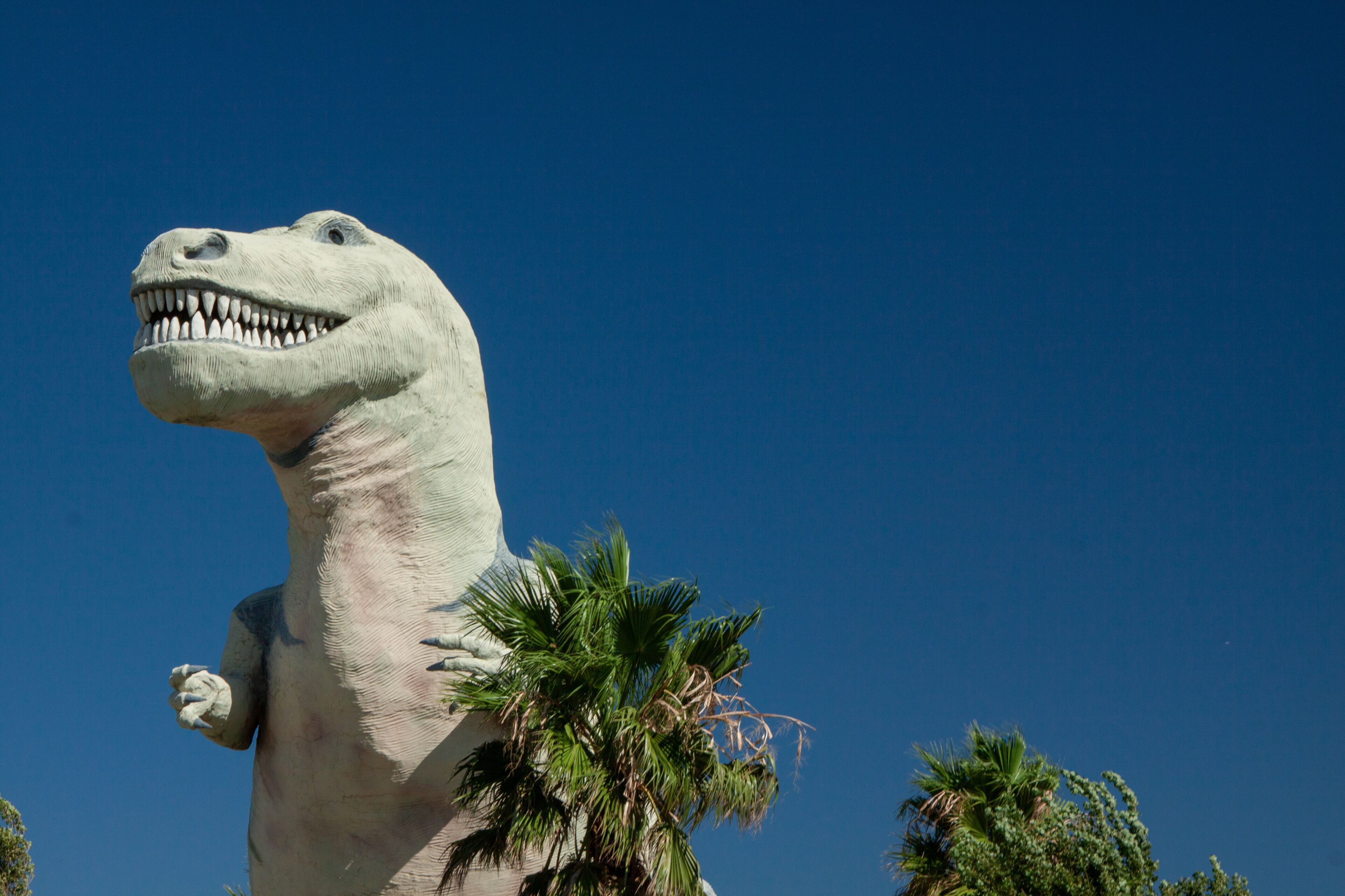 A large dinosaur statue with a clear blue sky in the background.