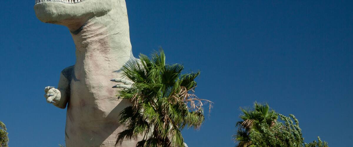 A large dinosaur statue with a clear blue sky in the background.