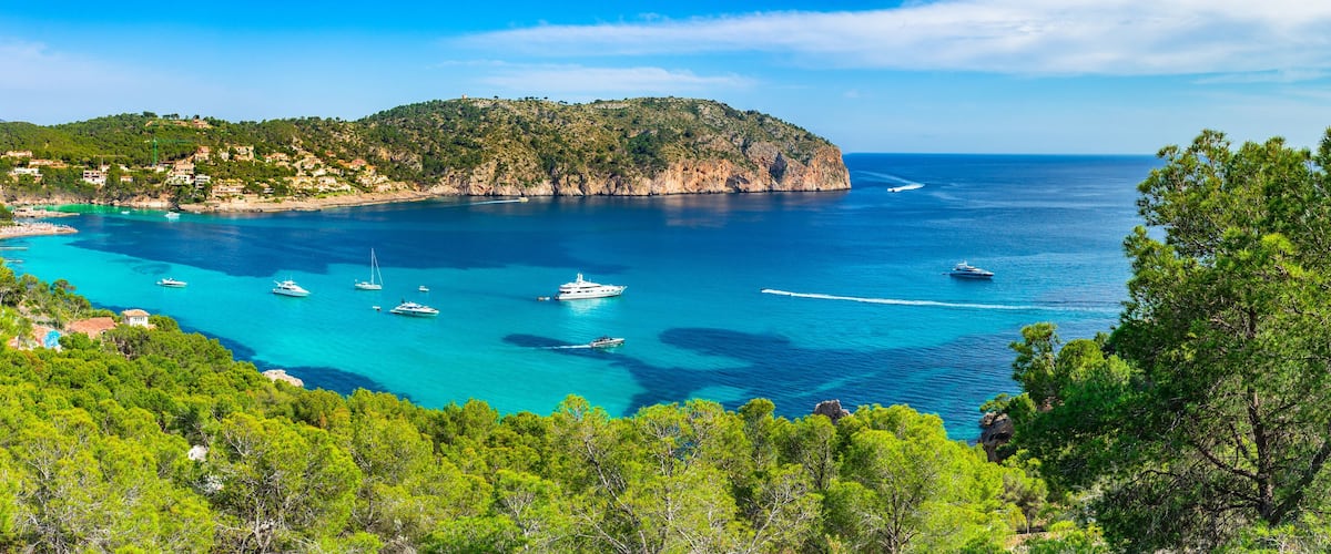 A coastal town with clear turquoise waters, boats, and lush greenery.