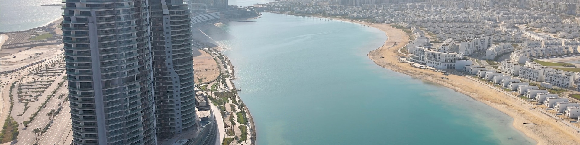 Aerial view of modern high-rise towers in New Alamein City between the Mediterranean Sea and a lagoon with a coastal highway, Egypt.