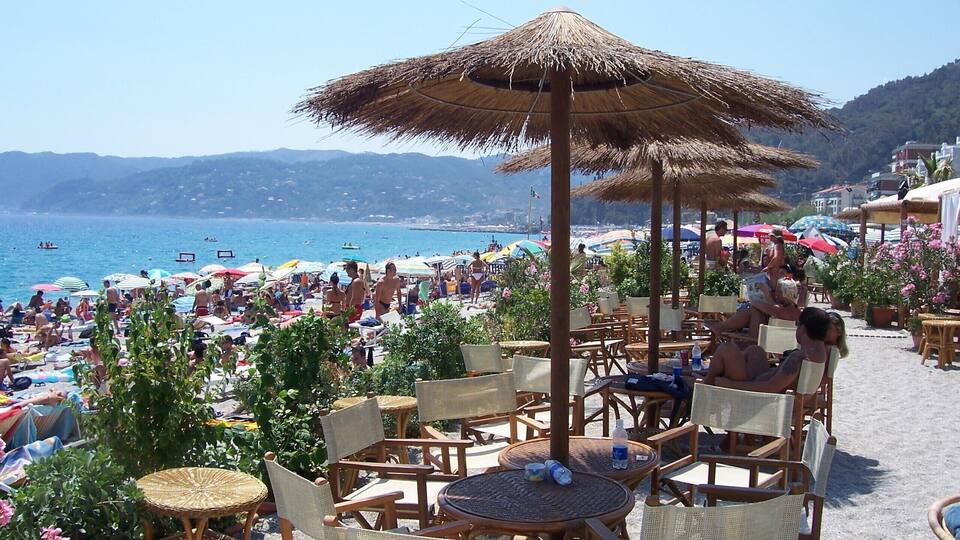 A crowded beach with umbrellas and beach chairs.