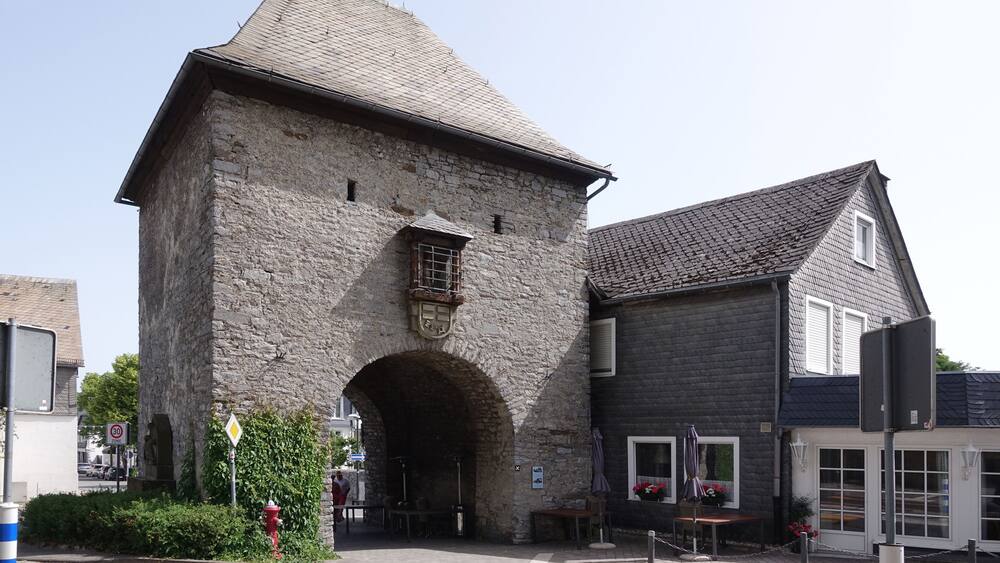 Un bâtiment en pierre doté d’une grande entrée en arc de cercle, un bâtiment plus petit attenant avec un toit sombre, et une borne d’incendie rouge au premier plan.