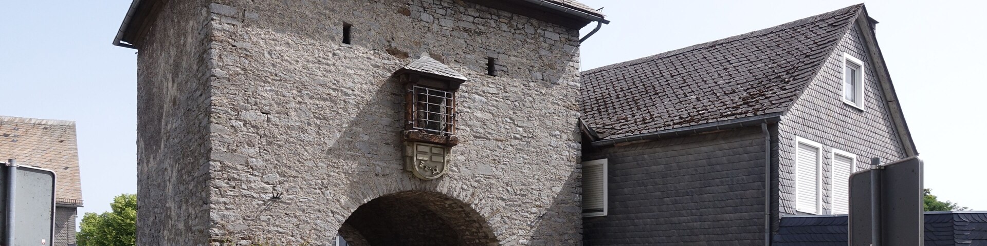 A stone building with a large archway entrance, a smaller attached building with a dark roof, and a red fire hydrant in the foreground.