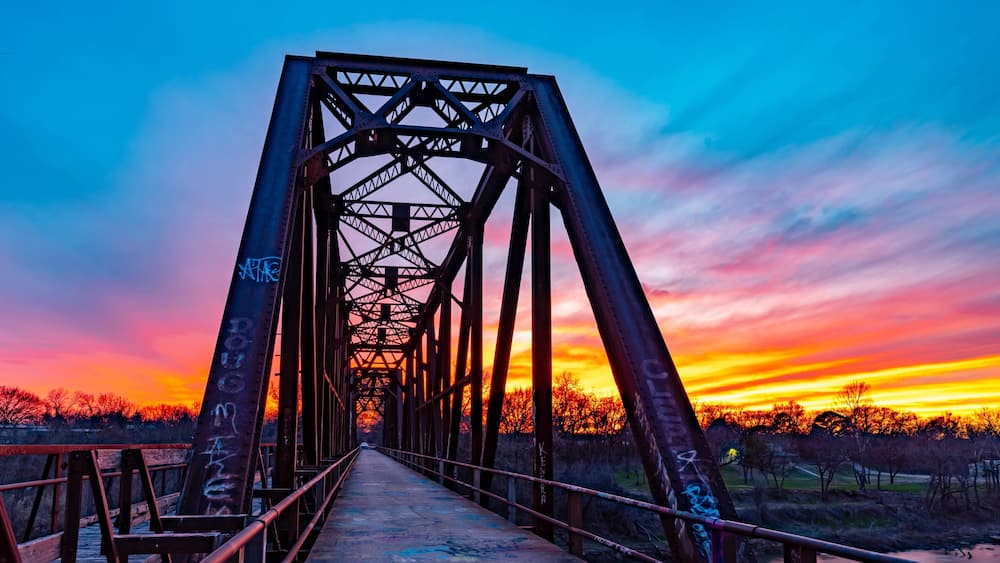 A sunset over a bridge with graffiti.