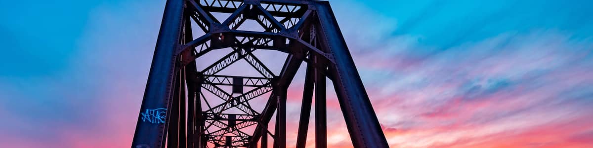 A sunset over a bridge with graffiti.