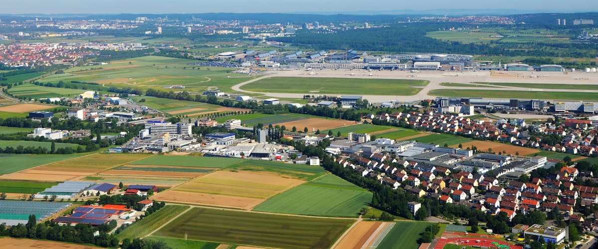 An aerial view of a town with residential areas, agricultural fields, and industrial buildings.