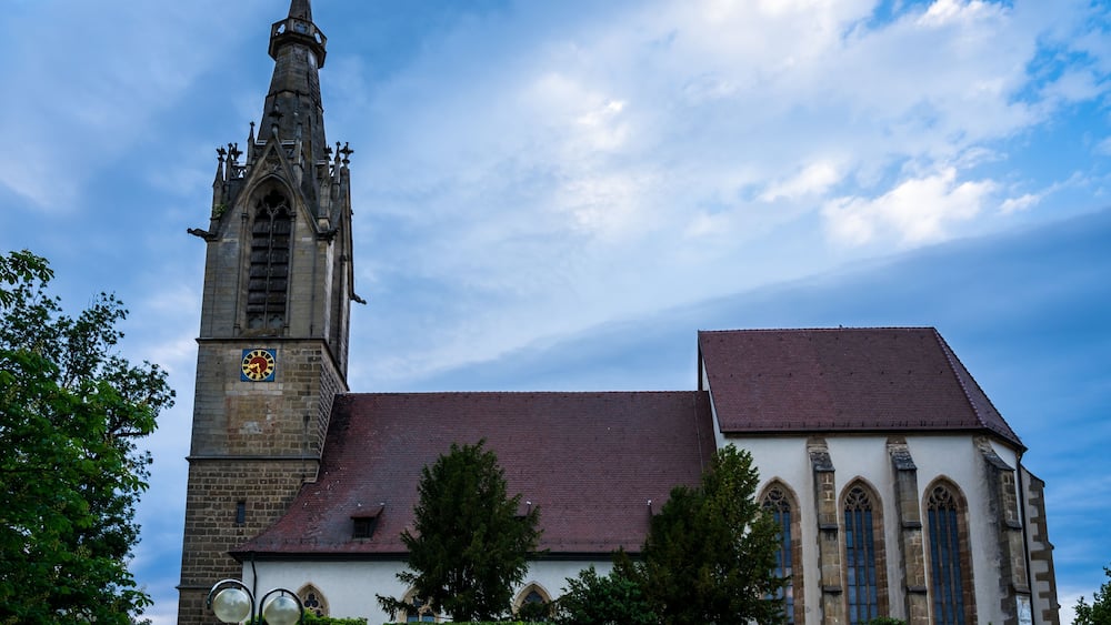 Eine historische Kirche mit einem hohen Glockenturm und einem roten Ziegeldach.