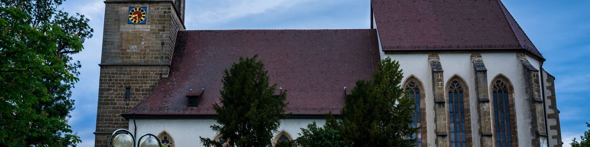 A historic church with a tall clock tower and a red-tiled roof.