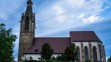 A historic church with a tall clock tower and a red-tiled roof.