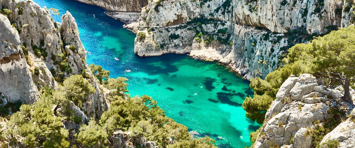 A coastal cliff with turquoise waters and dense greenery.