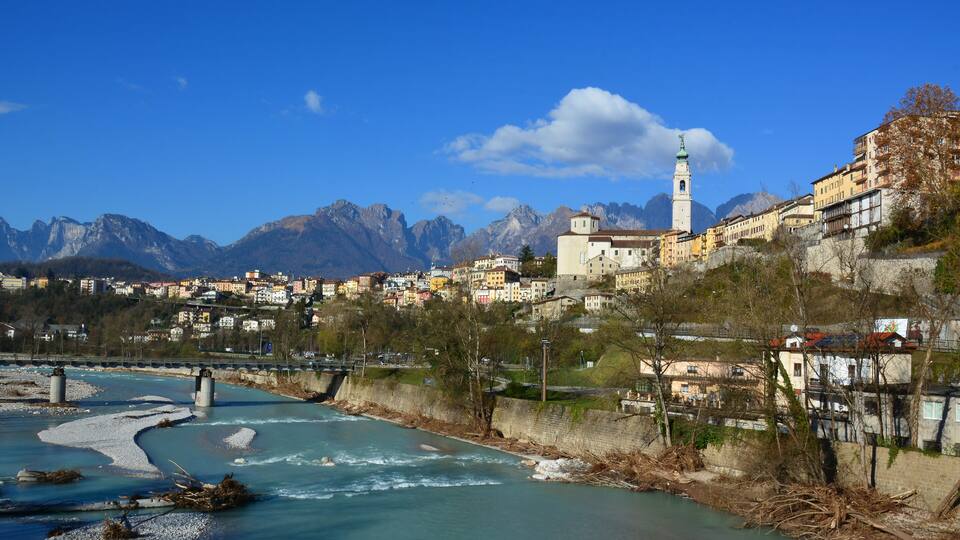 A river flowing through a town with mountains in the background.