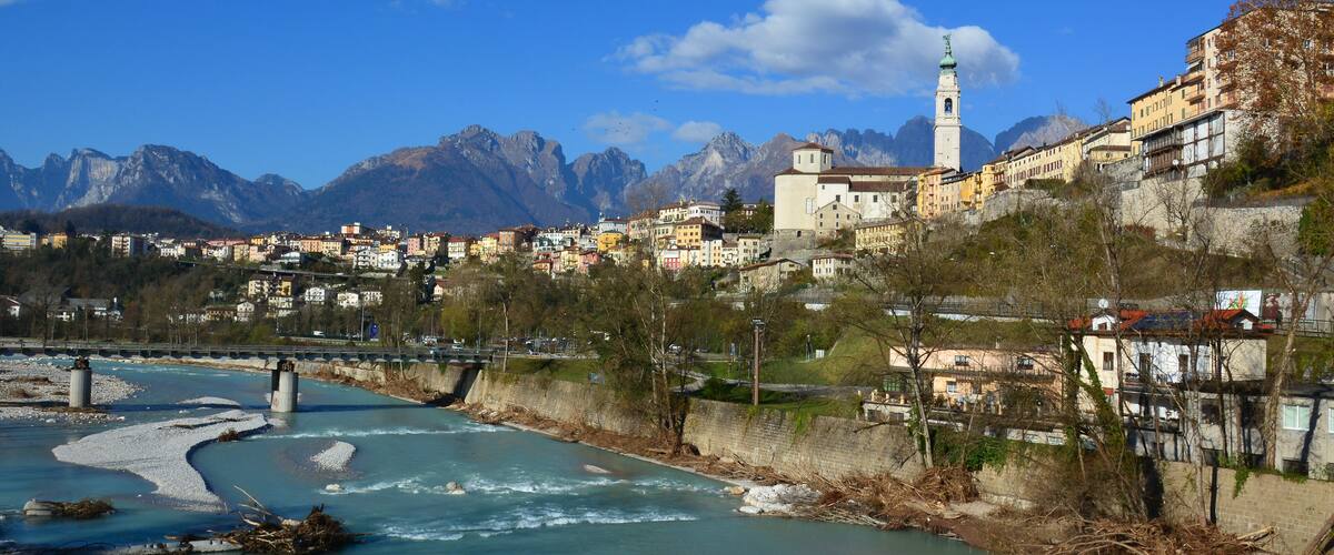 A river flowing through a town with mountains in the background.