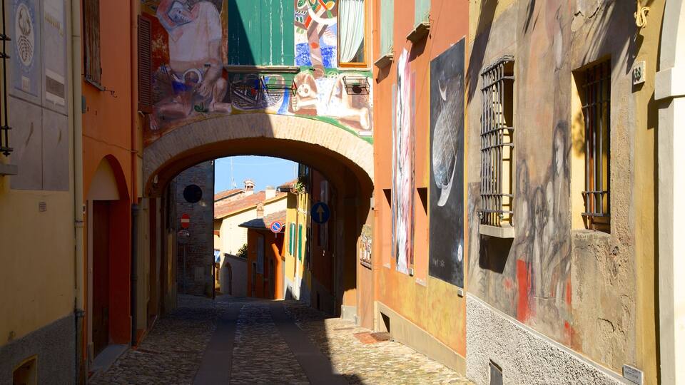 A narrow cobblestone street with colorful buildings and an archway.