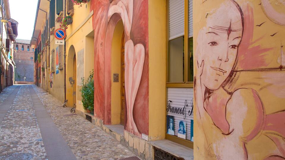 A cobblestone street lined with colorful buildings, one featuring a large mural and a 'Francesco' sign.