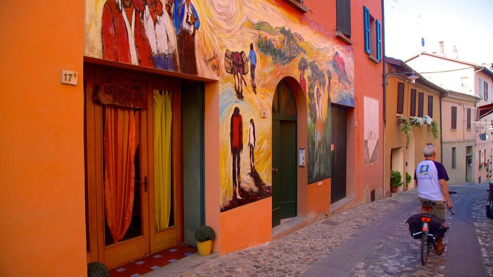 A colorful street with a mural, a man on a bicycle, and a cobblestone road.