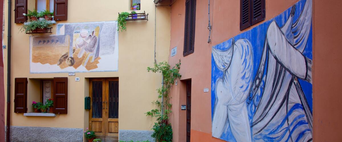 A narrow cobblestone street with a building featuring a large mural and potted plants.