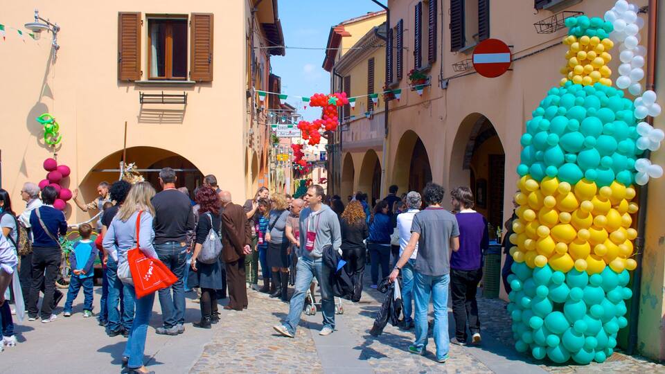 A crowded street with people walking, a large balloon sculpture, and buildings with arched windows.