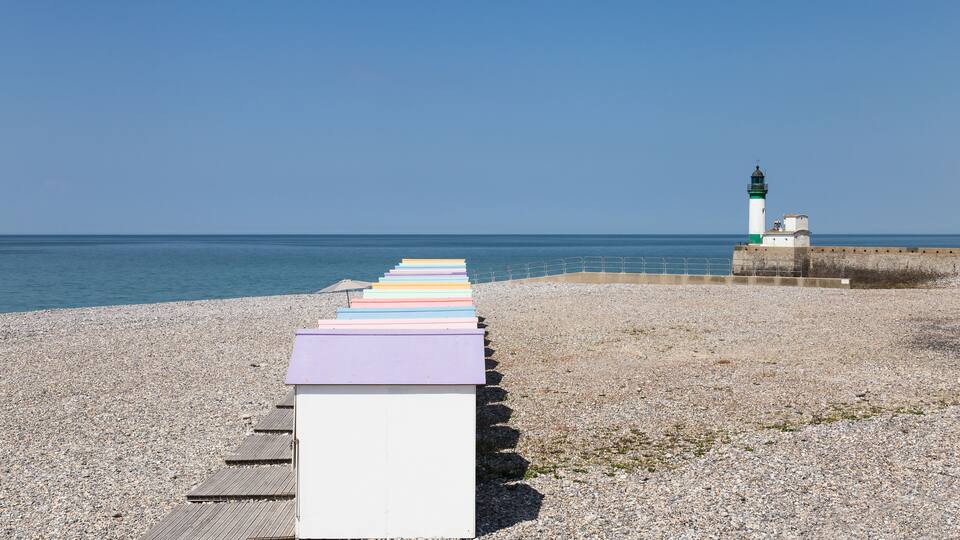 A pebbled beach with colorful steps leading to a lighthouse.
