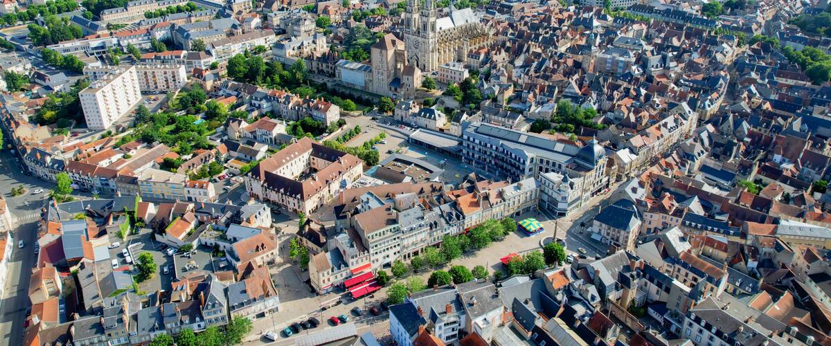 A historic European cityscape with dense architecture, a prominent cathedral, and a river.