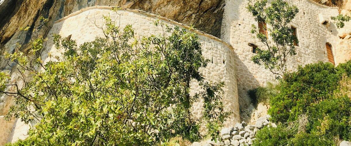 A rugged mountain landscape with rocky cliffs and a stone wall.