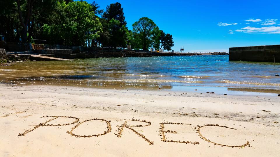 A beach with the word 'POREC' written in the sand.