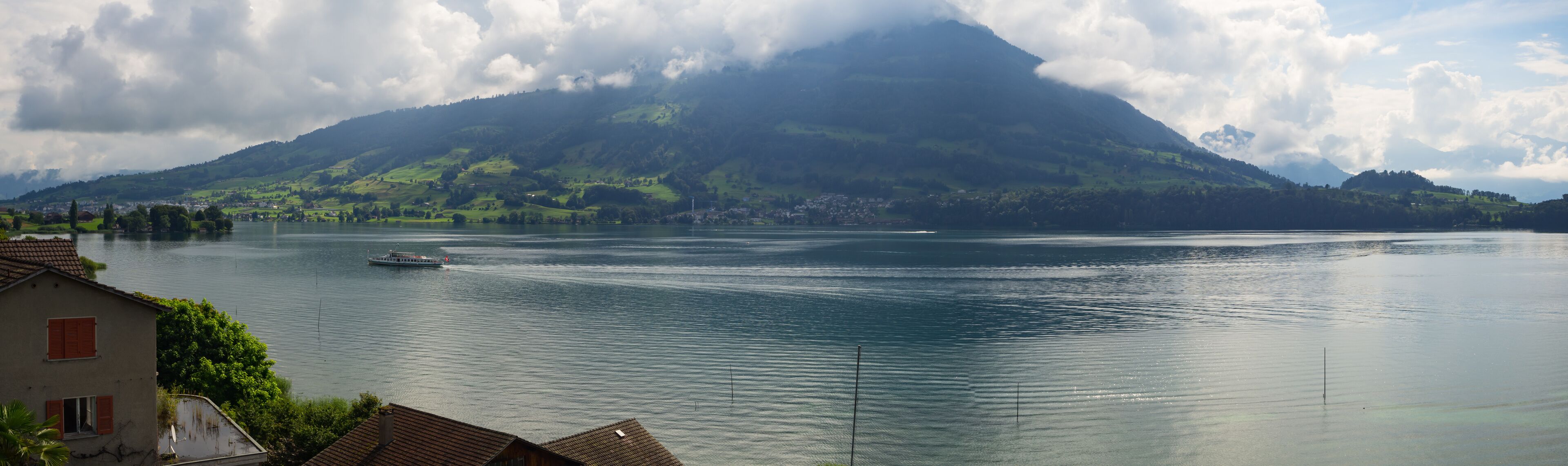 A lake with a boat, a mountain, and houses in the foreground.