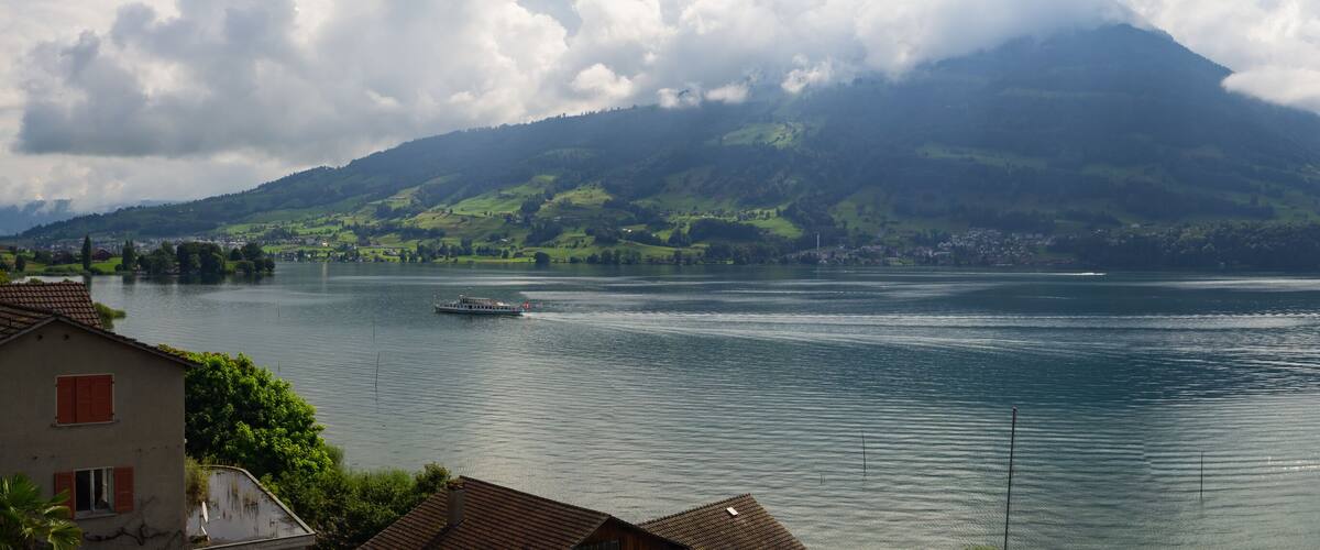 A lake with a boat, a mountain, and houses in the foreground.