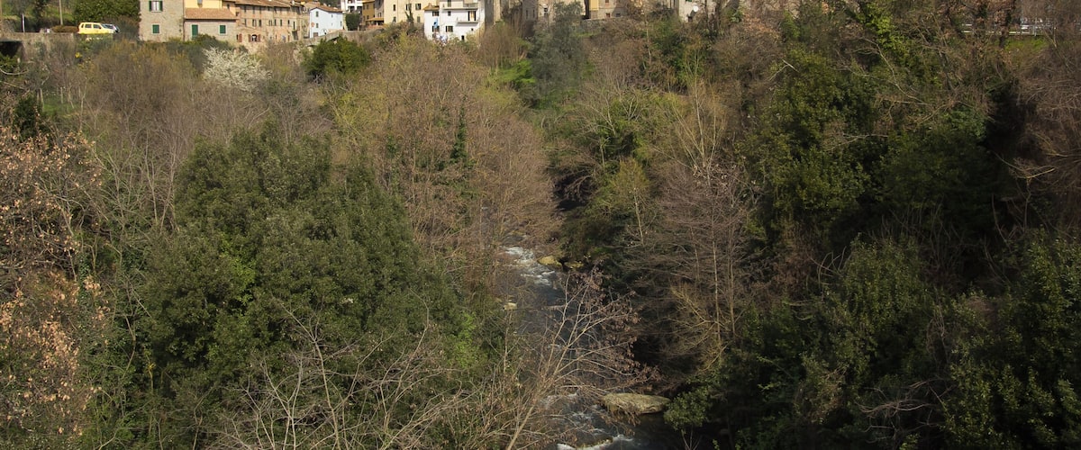 Un pueblo montañoso con edificios ubicados entre árboles y un río que serpentea.