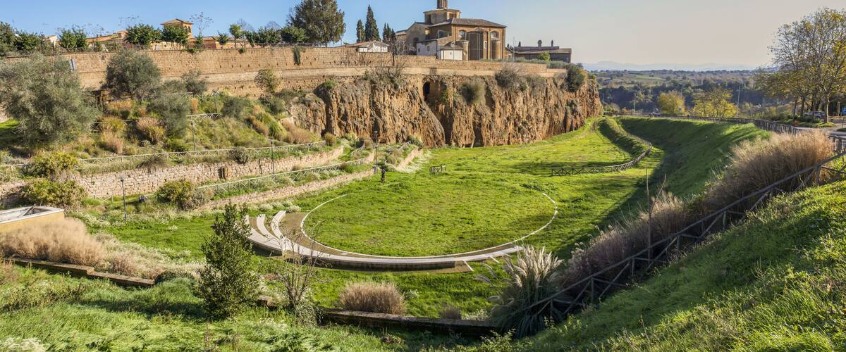 A historic building on a cliff, a grassy area with a curved path, and a stone wall.