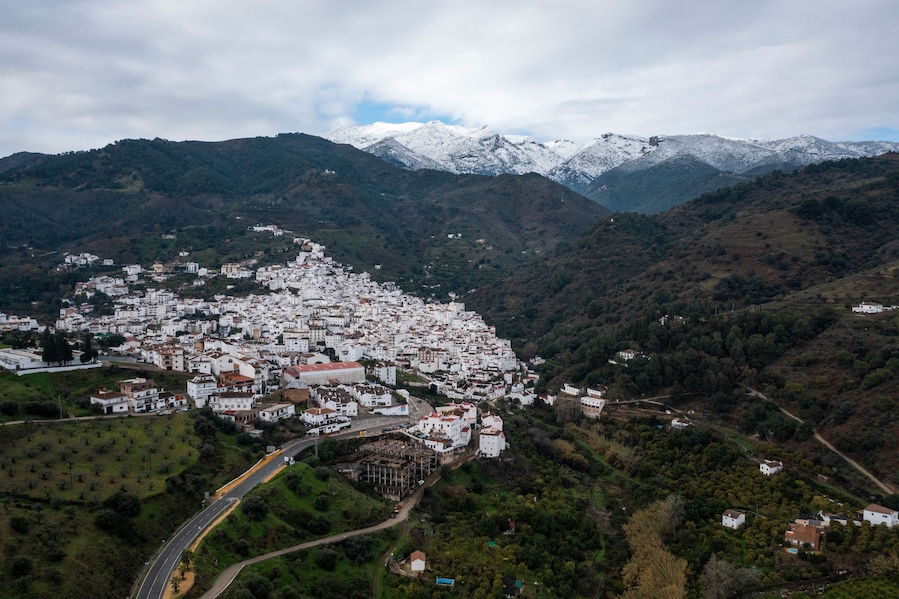 Une ville de montagne aux bâtiments blancs, nichée dans la vallée et entourée de sommets enneigés.