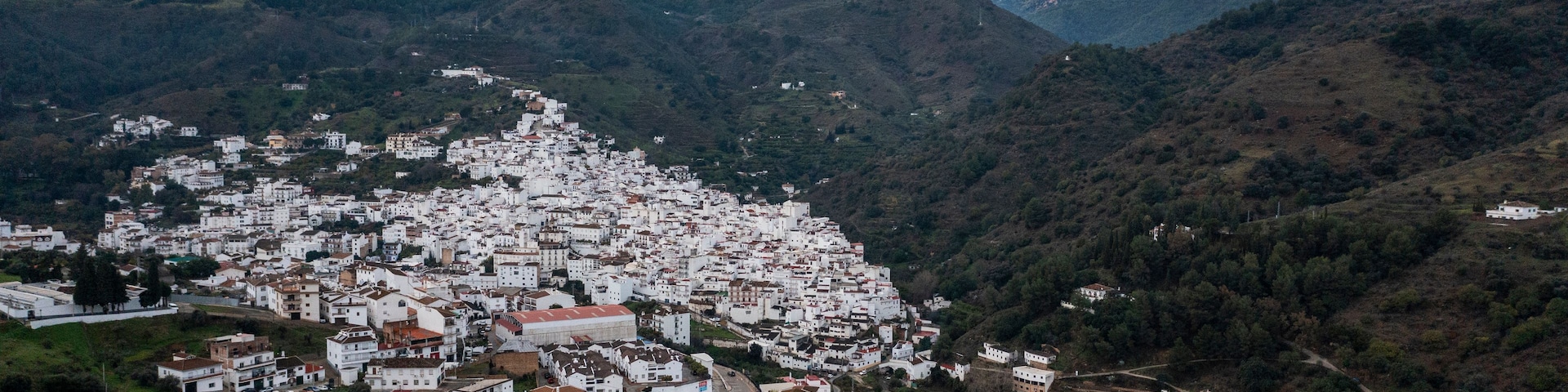 A mountainous town with white buildings nestled in the valley, surrounded by snow-capped peaks.