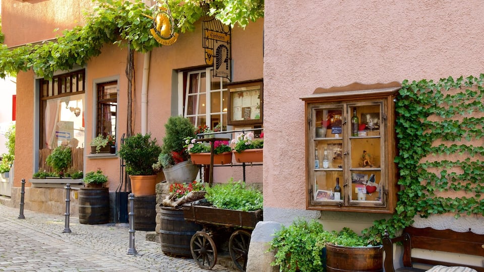 A charming European street with a building adorned with ivy, potted plants, and a vintage cart.