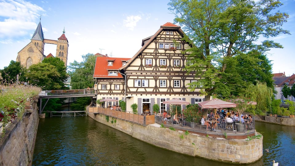 A riverside town with a traditional half-timbered house, a church, and a bridge.