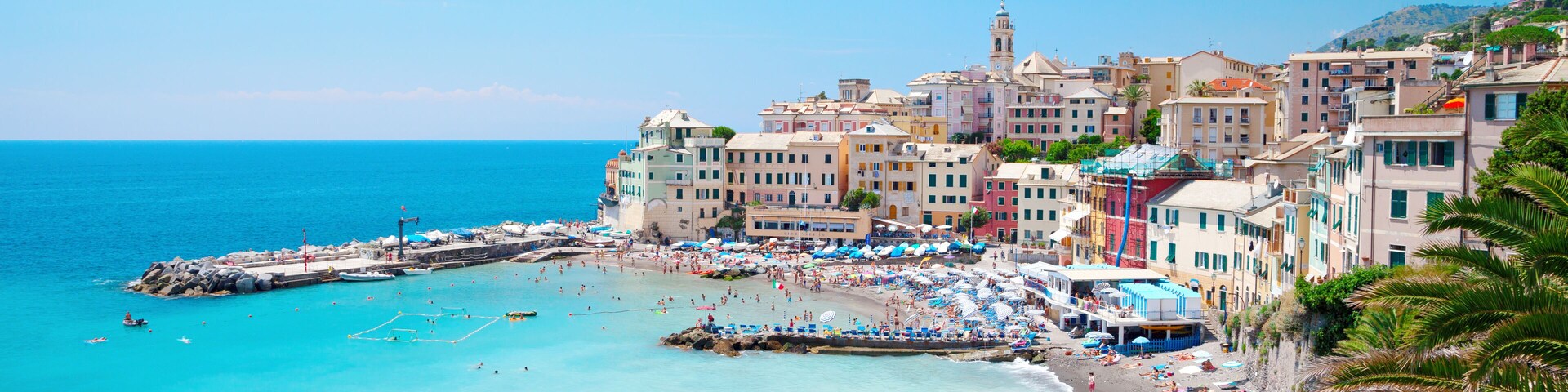 Un pueblo costero con edificios coloridos, una playa y un muelle que se adentra en el mar.