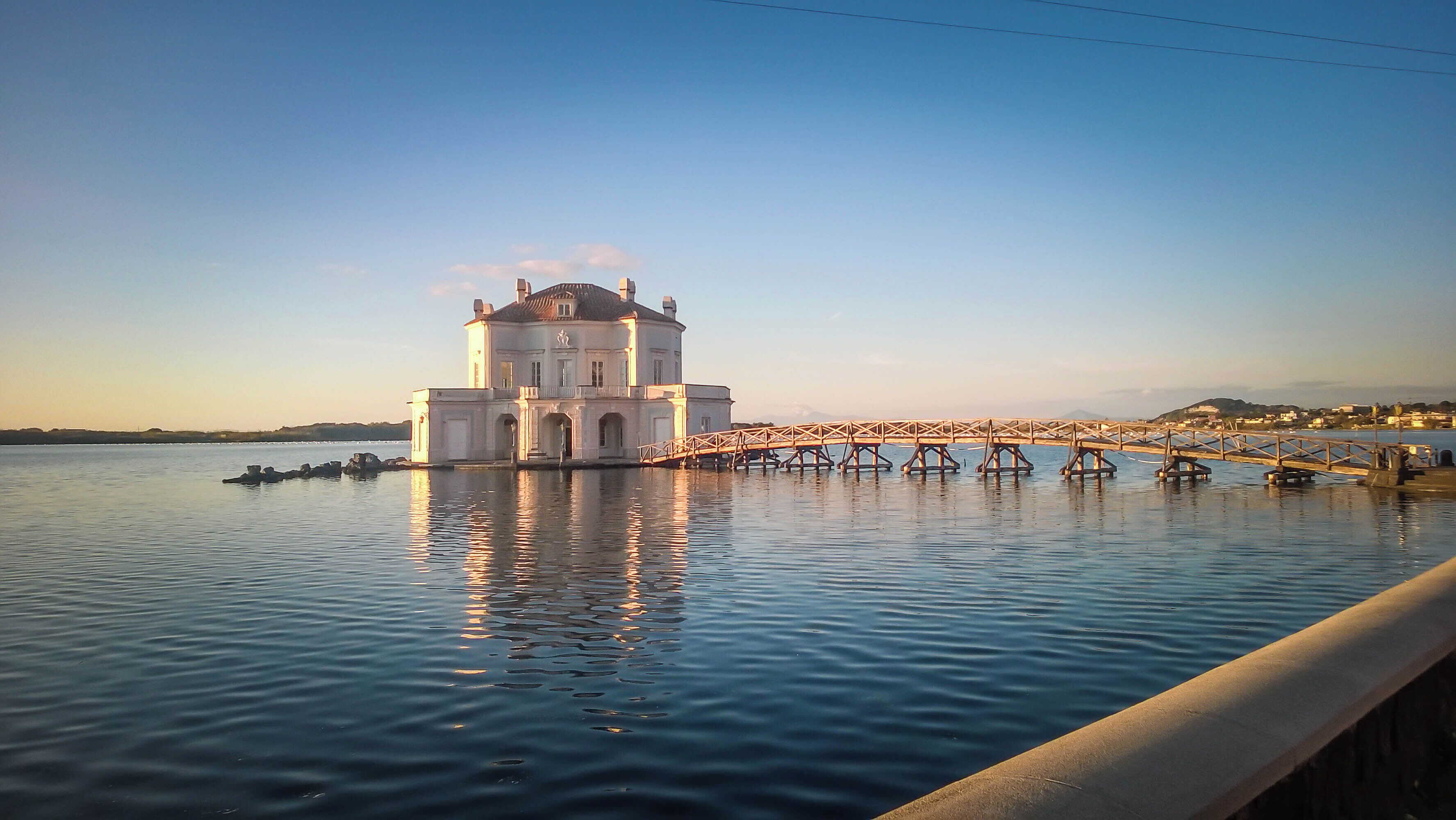 A large white building with a bridge over calm water.