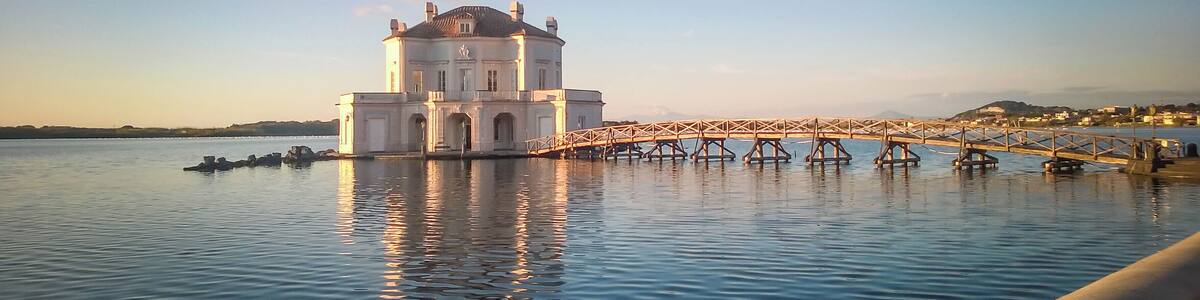 A large white building with a bridge over calm water.