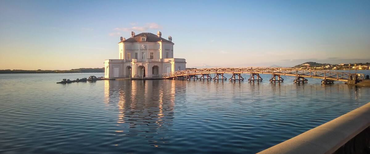 A large white building with a bridge over calm water.
