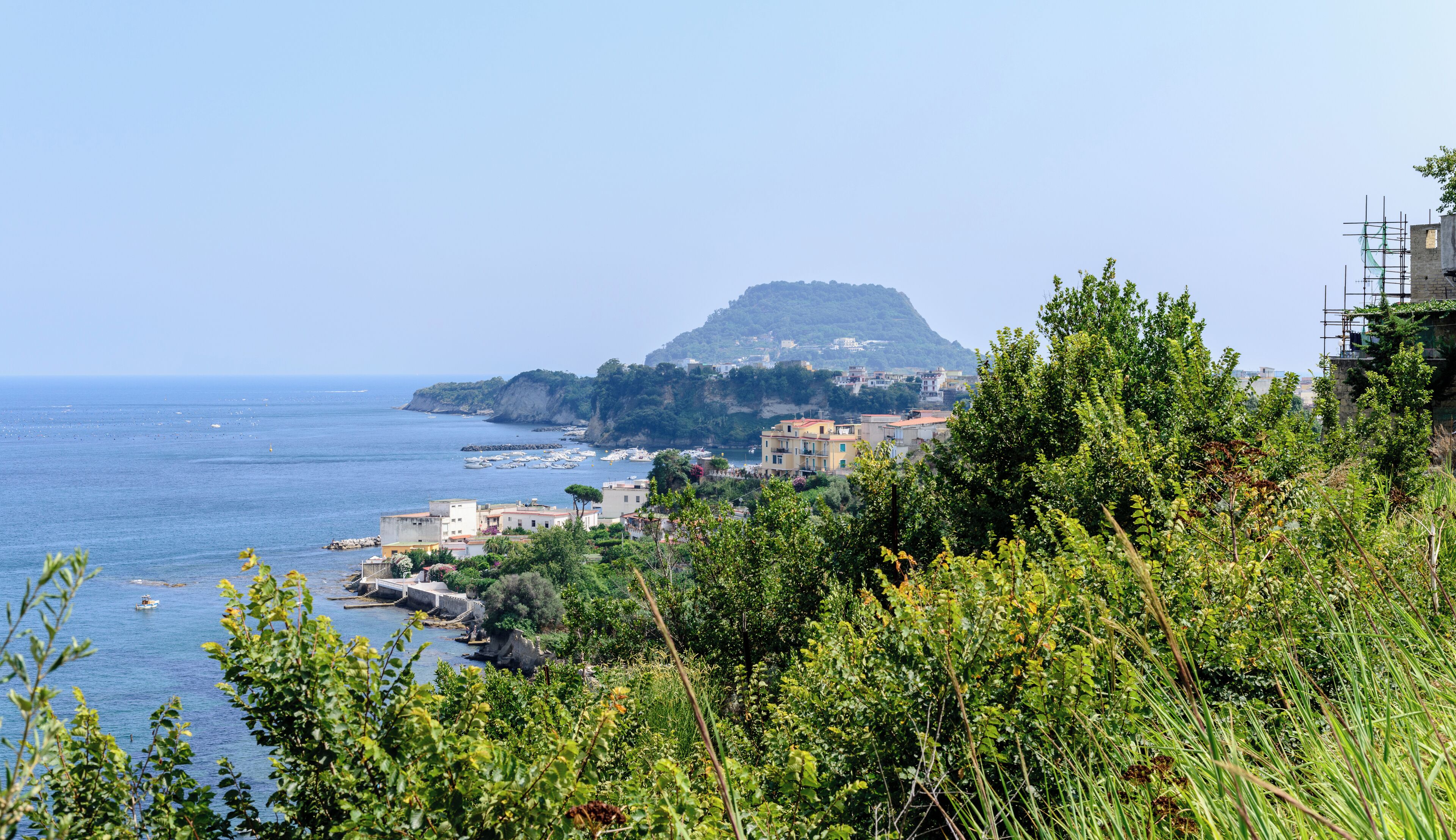 A coastal town with buildings, a hill, and boats on the water.