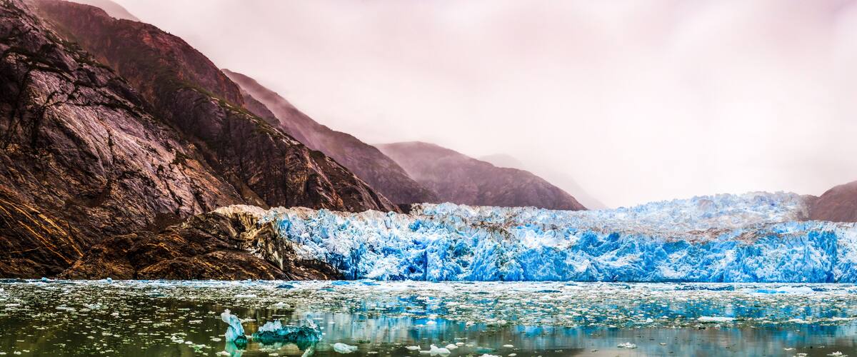 A glacier with icebergs in a mountainous area.