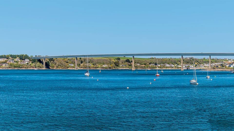 A coastal town with a bridge, clear blue waters, and sailboats.
