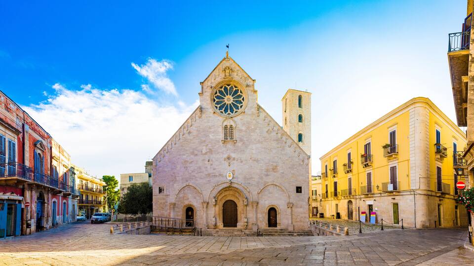 A historic church with a large rose window, a bell tower, and a cobblestone plaza.