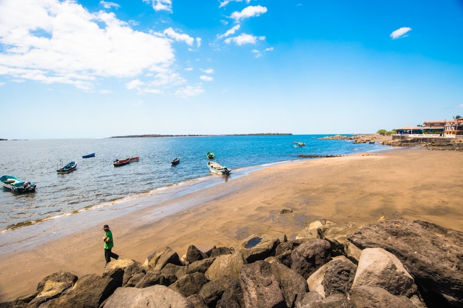 Una playa con barcos, rocas y cielo despejado.