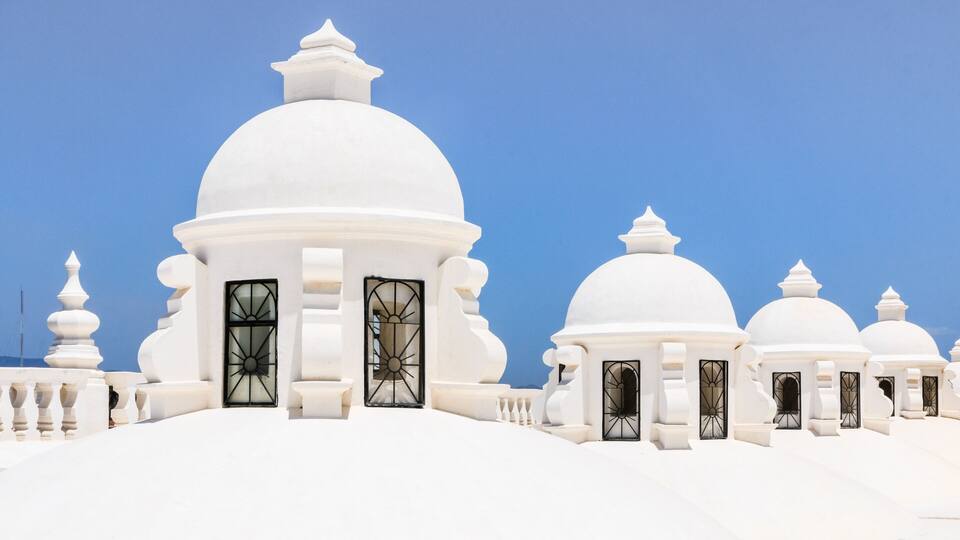 White domed buildings with black window frames and a clear blue sky.